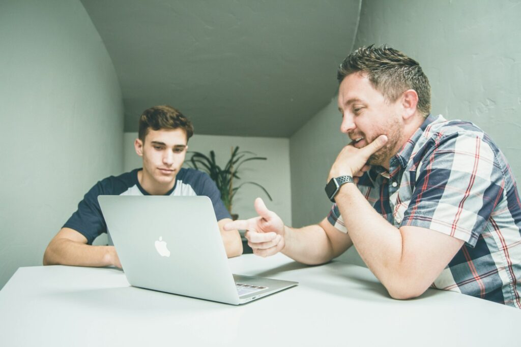 Colleague guiding a new team member on a laptop